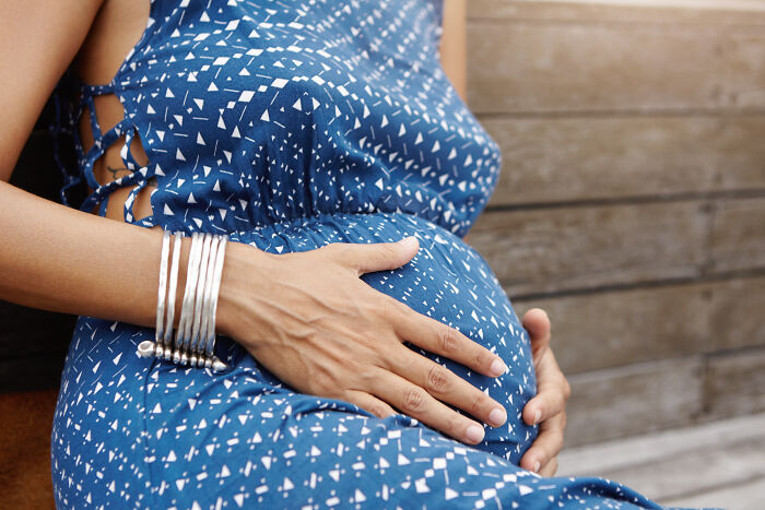 Pregnant woman in blue dress holding baby bump revealing family secrets