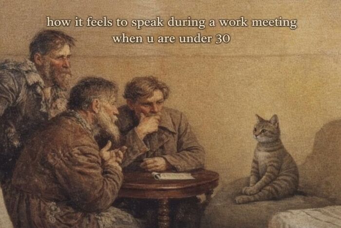 Cat sitting alone at a table with older men, caption about work meetings for under 30