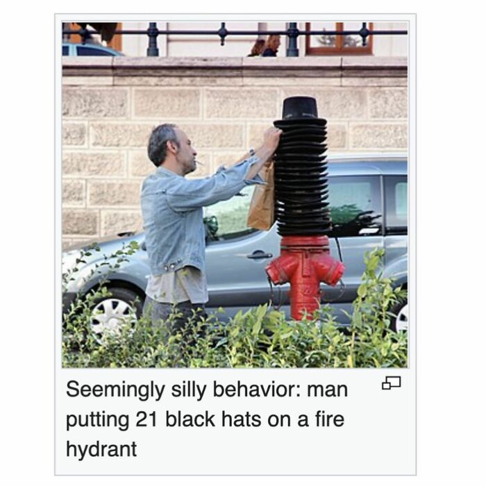 Man stacking 21 black hats on a fire hydrant as a quirky act