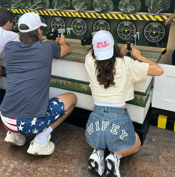 Couple playing carnival game with wife of the party hat and wifey shorts