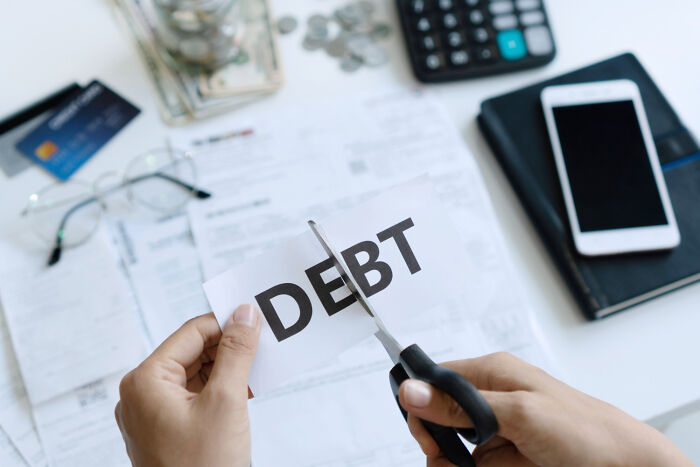 Hands cutting a paper with the word DEBT, representing disturbing things people learned about their friends.