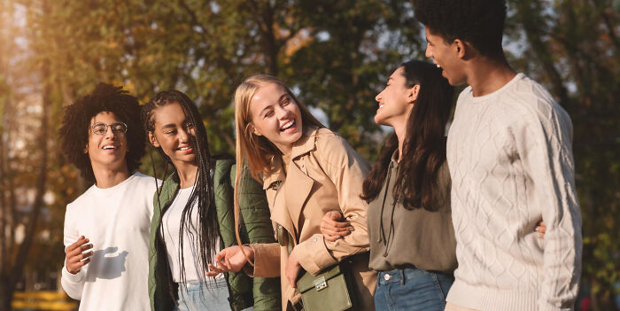 A group of diverse friends laughing and walking outdoors, contrasting with disturbing things people learn about friends.