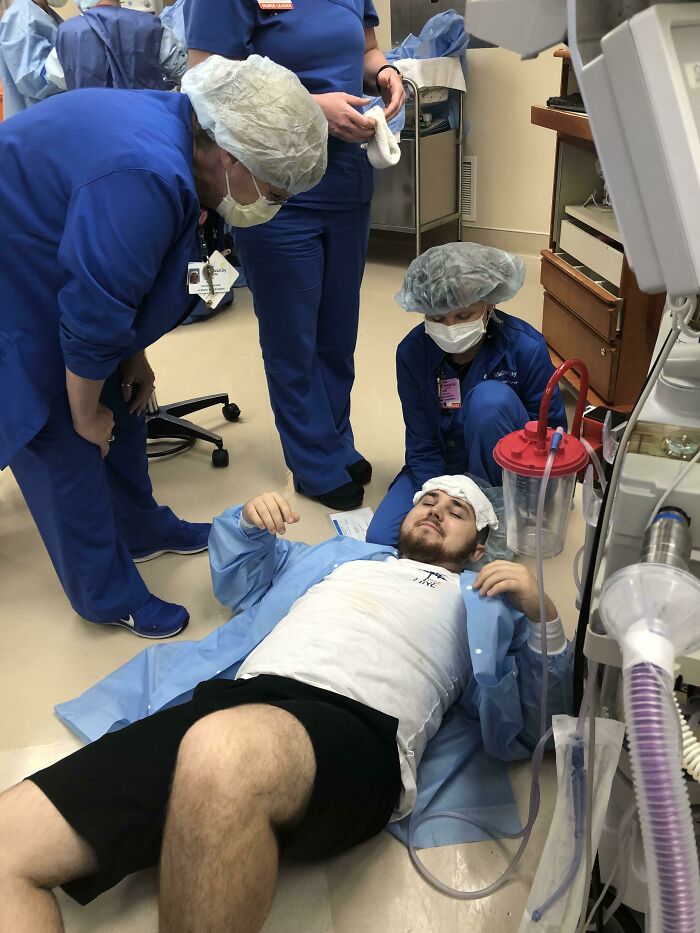 Man in hospital gown lying on floor with medical staff attending, funny or cringe fail scene