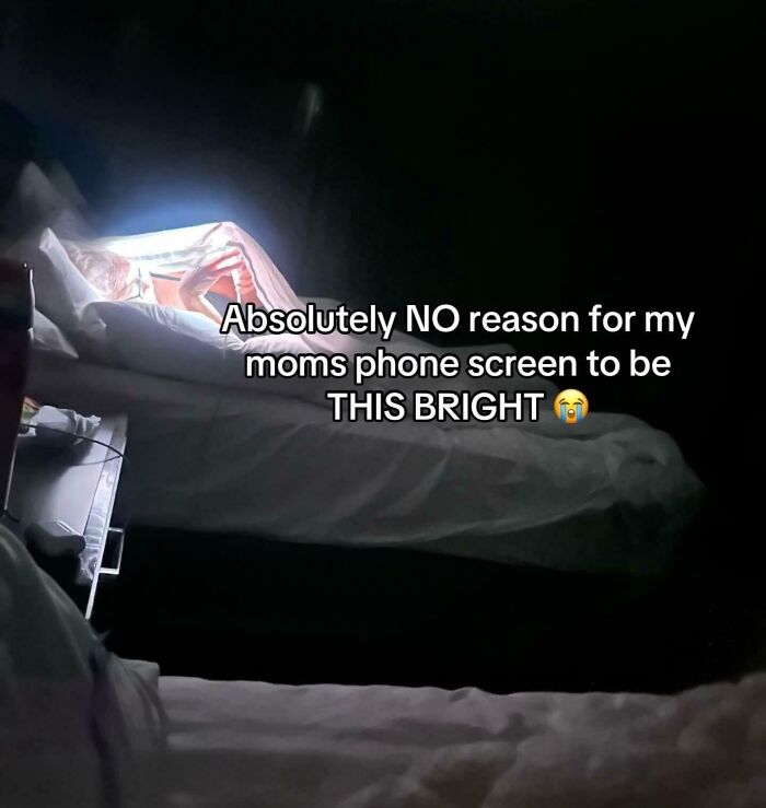 Bright phone screen shining in dark room with funny caption