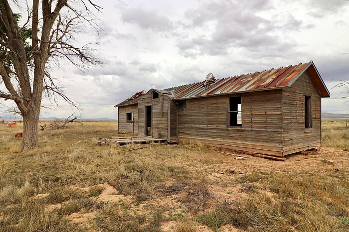 Abandoned wooden house in rural field representing forgotten places urban exploration