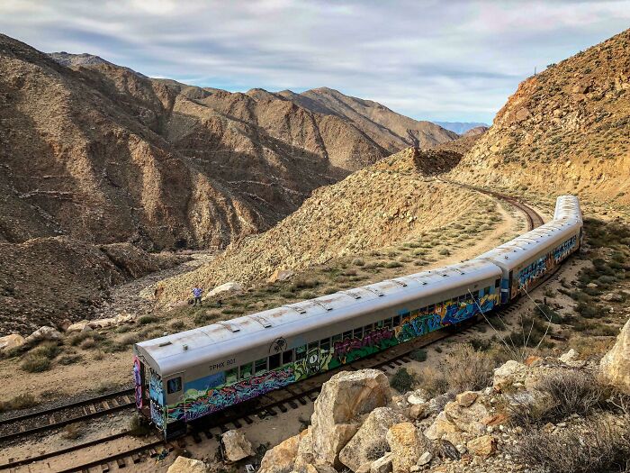 Graffiti-covered abandoned train in desert mountains on urban exploration
