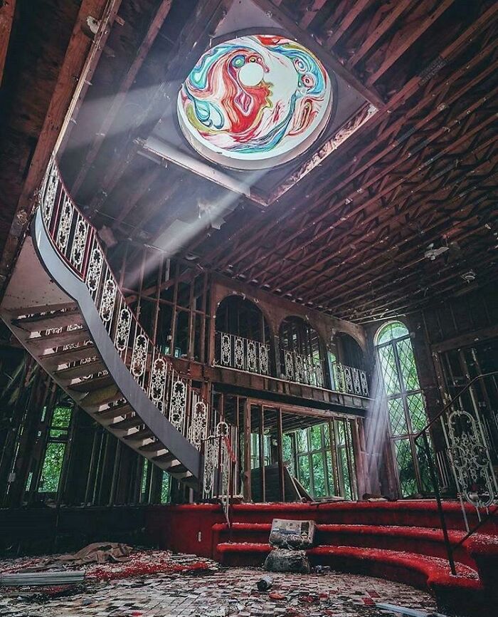 Abandoned mansion interior with spiral staircase and colorful skylight on ceiling urban exploration