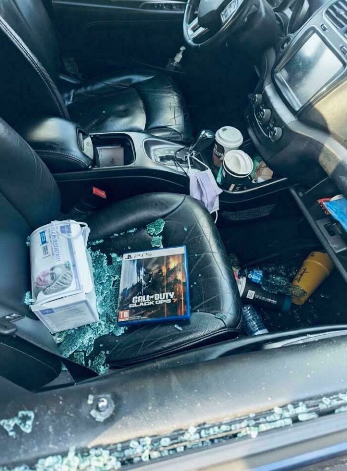 Car interior with broken window and Call of Duty game on seat