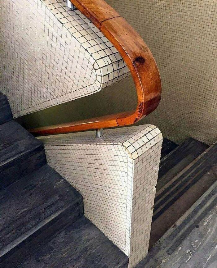 Innovative stair railing with tiled curved corner and wooden handrail