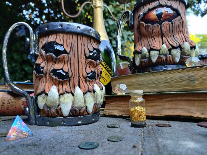 Unique monster-themed mugs with sharp teeth on outdoor table