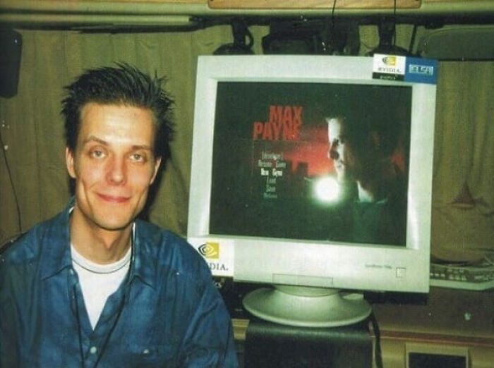 Old photo of a man smiling next to a monitor displaying a Max Payne game