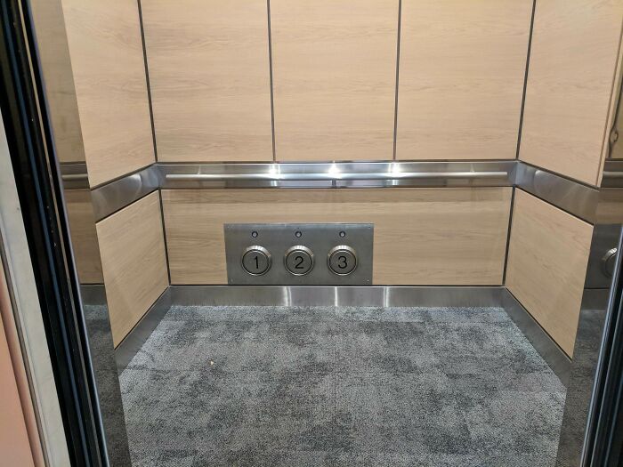 Elevator interior with floor buttons designed low on wood paneling wall