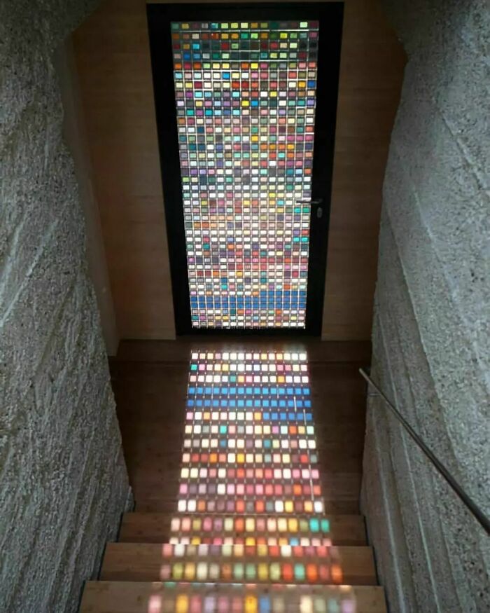 Colorful stained glass door casting vibrant light on staircase showing designer genius
