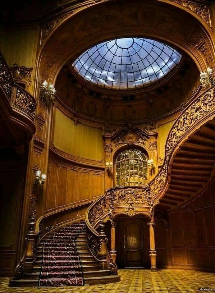 Intricately carved wooden staircase with curved design and dome skylight above