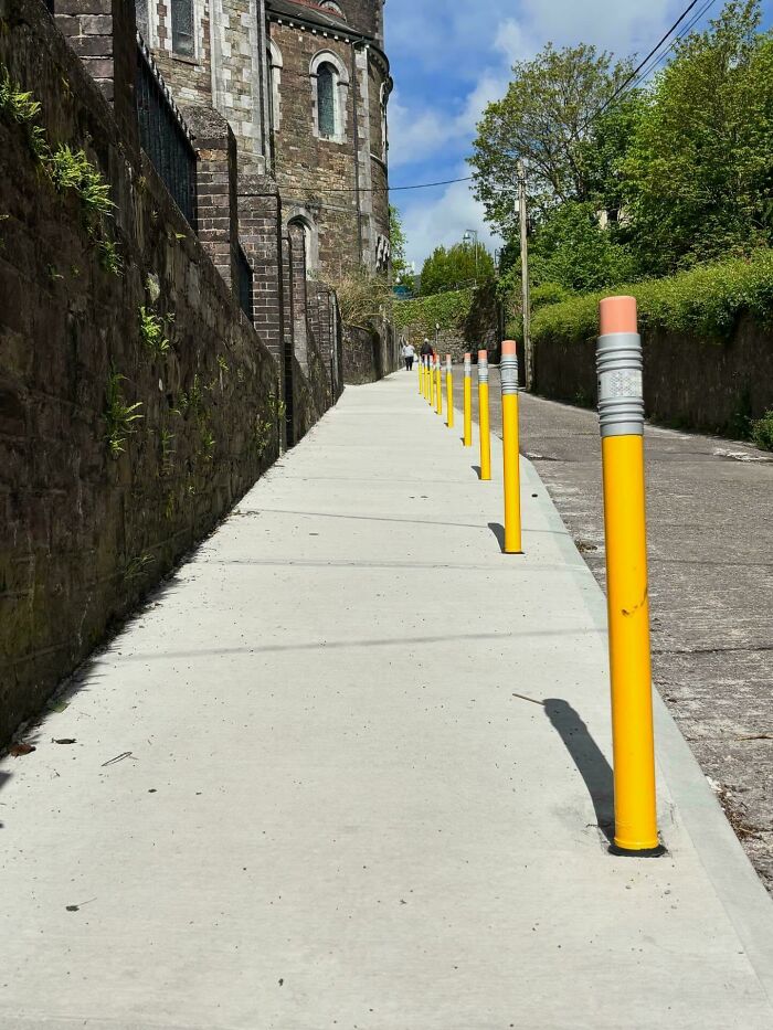 Creative brain design of pencil-shaped yellow bollards on a sidewalk