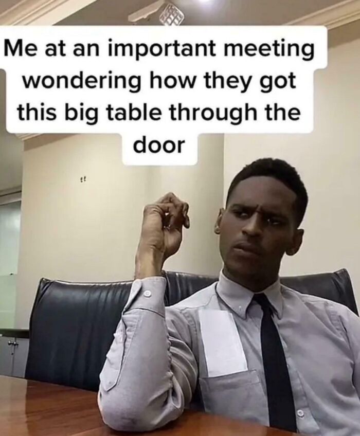 Man at meeting puzzled about fitting a big table through a door