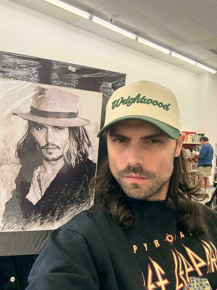 Amazing Goodwill thrifted man in front of a Johnny Depp-style portrait