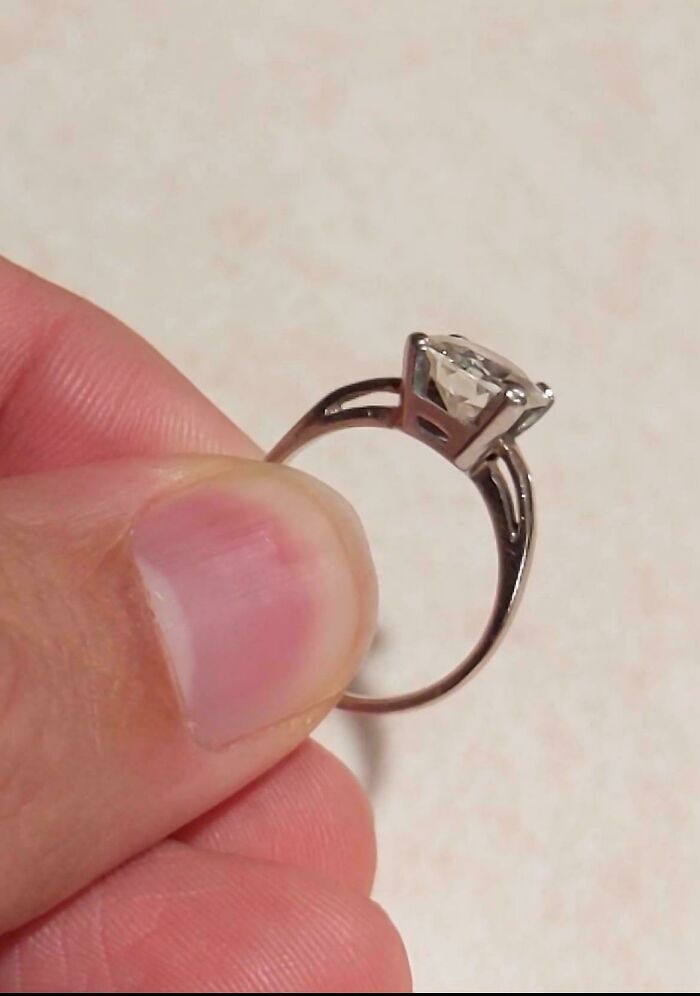 Thrifted engagement ring with a clear stone held between fingers
