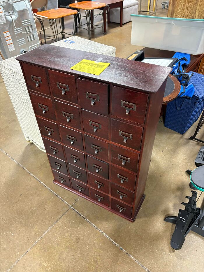 Vintage wooden cabinet with many drawers with sold sign at Goodwill shop