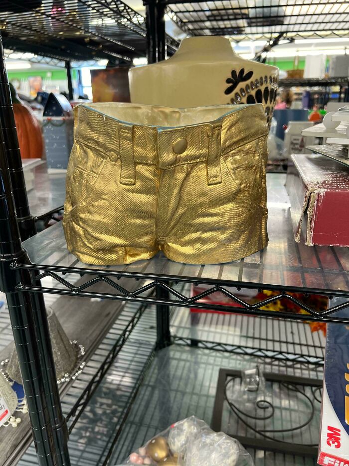 Decorative gold miniature shorts on thrift store shelf among other items