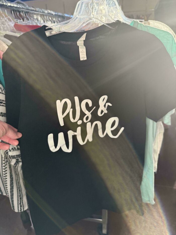 A black t-shirt with PJS & wine printed on it, exemplifying bad clothing designs.