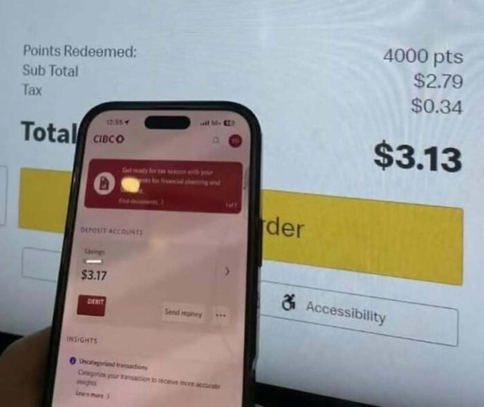 Phone showing bank balance of 3.17 held in front of 3.13 purchase total on screen