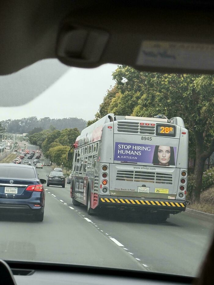 Back of city bus with stop hiring humans advertisement on highway