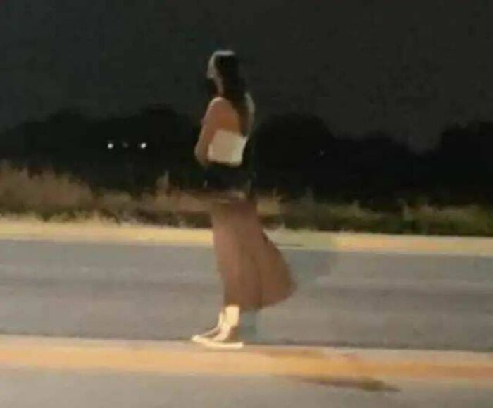 Woman standing alone at night on empty road in eerie setting horror stories