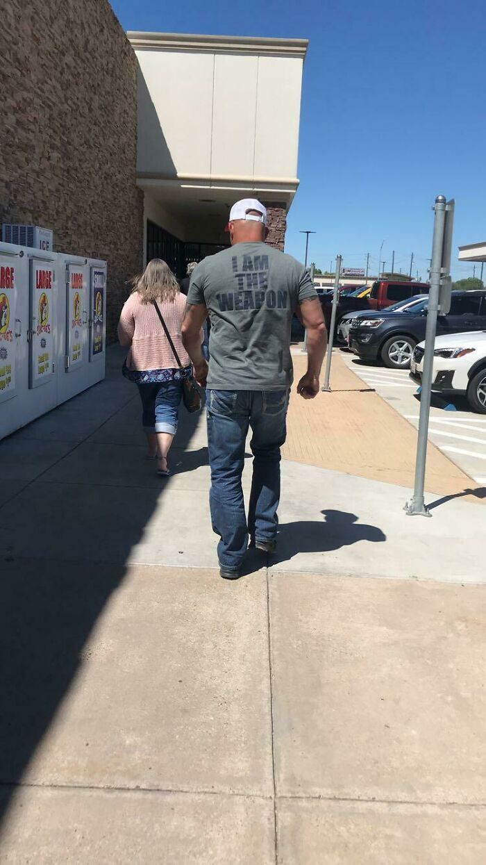 Man walking outdoors wearing a shirt saying I am the weapon