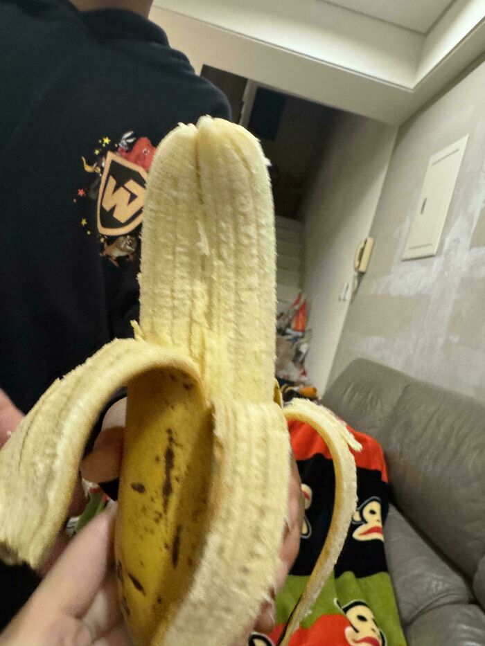 Peeled banana with unusual forked tip held indoors