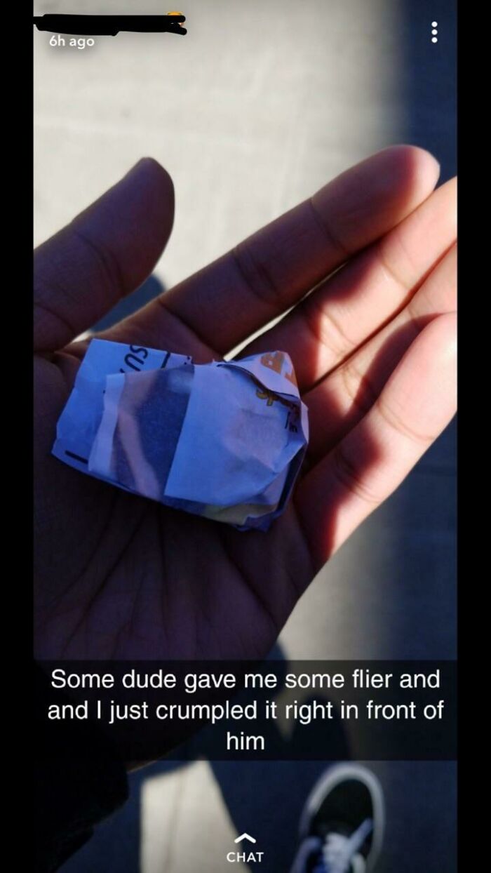 Hand holding a crumpled paper flier showing a defiant attitude