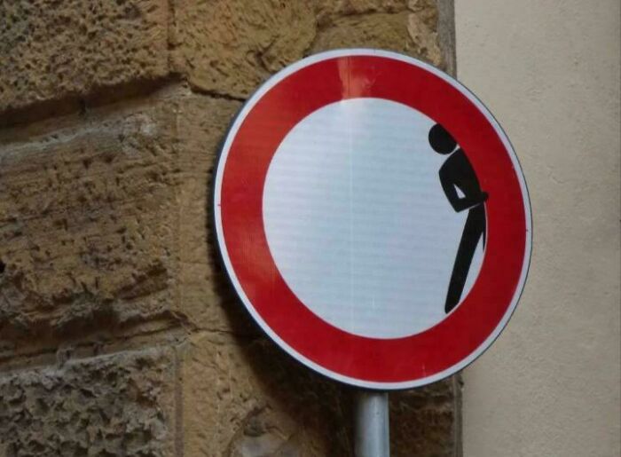 Comical no entry road sign altered with a peeking person illustration