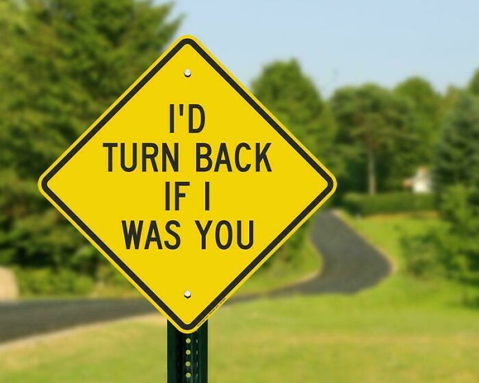 Funny cautionary road sign advising to turn back