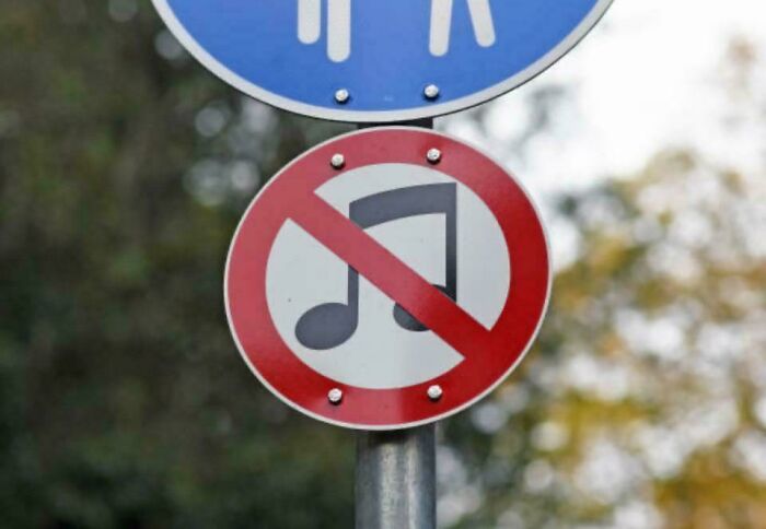 No music allowed sign below pedestrian sign in outdoor setting
