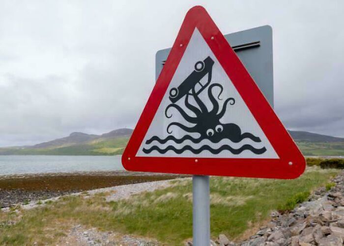 Humorous road sign showing car attacked by octopus near water