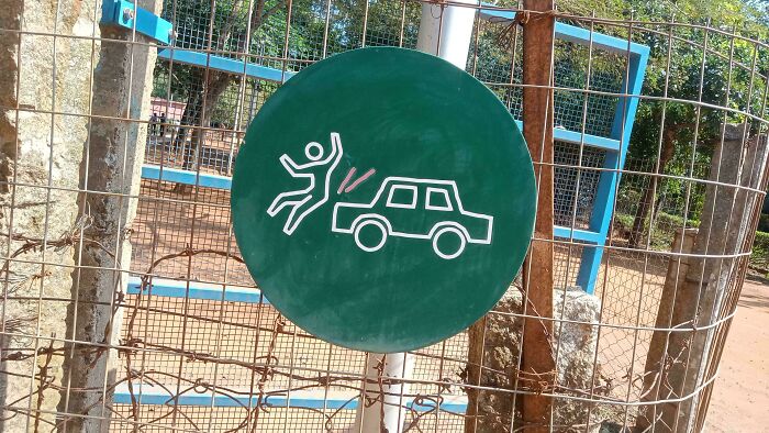 Warning sign depicting a person being hit by car illustration on a green circular board