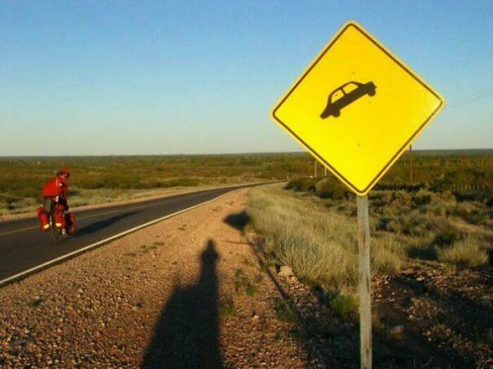 Humorous road sign showing a car jumping off the road in a rural area