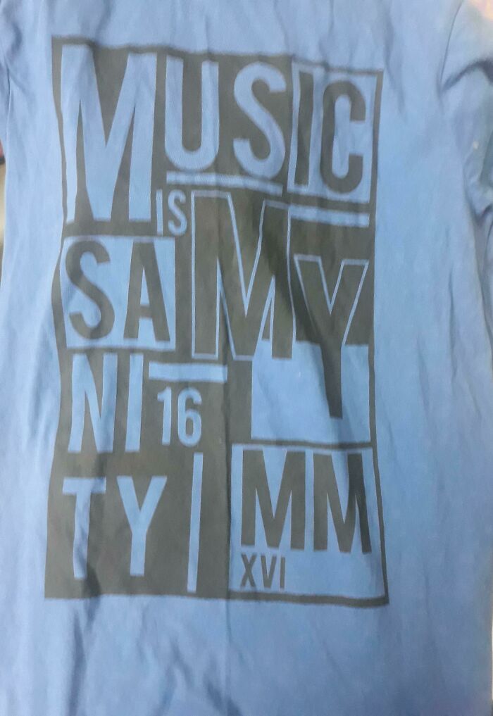 A blue t-shirt with illegible text in black block letters, a prime example of bad clothing designs.