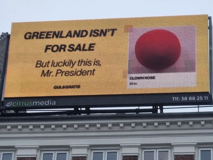 A billboard sign that says Greenland Isn't For Sale, with a picture of a clown nose, illustrating airport chaos.