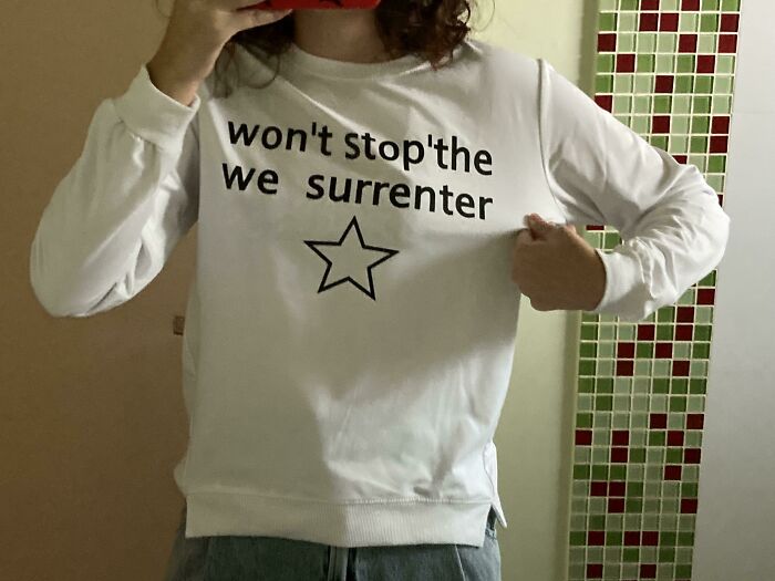 White long-sleeve shirt with the phrase 'won't stop the we surrenter' and a star, highlighting bad clothing designs.