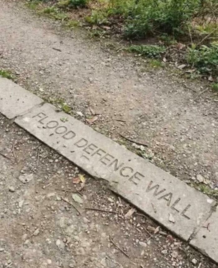 Concrete slab labeled flood defence wall on dirt path