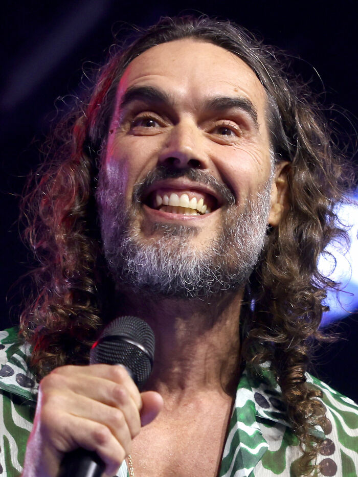 Close-up of Russell Brand holding a microphone during a live performance