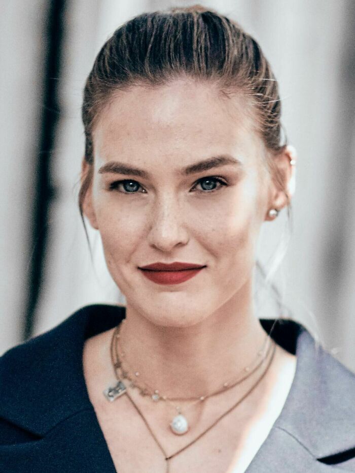 Close-up portrait of Bar Refaeli with red lipstick and layered necklaces