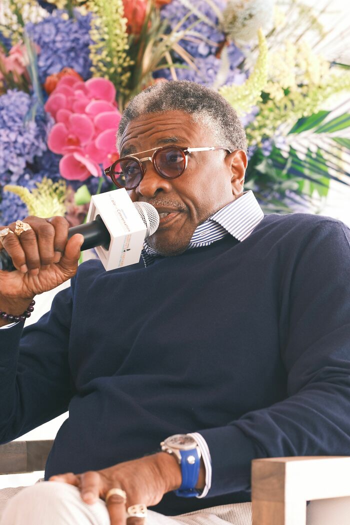 Keith David speaking into microphone during interview with floral background