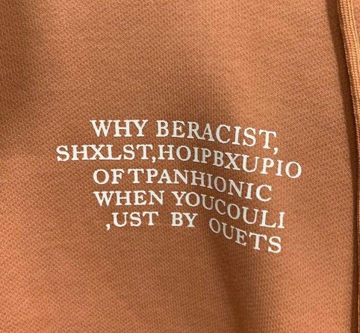 Close-up of a brown fabric with jumbled, nonsensical white text, representing bad clothing designs.