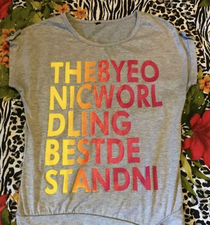 A gray T-shirt with poorly arranged, colorful letters that are unreadable, highlighting a bad clothing design.