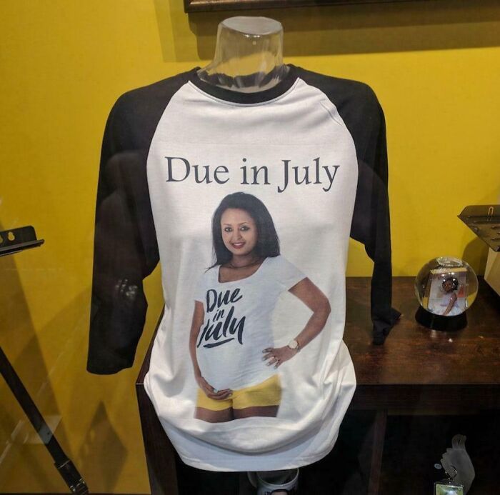 A T-shirt on a mannequin with a photo of a pregnant woman and the text Due in July, highlighting bad clothing designs.