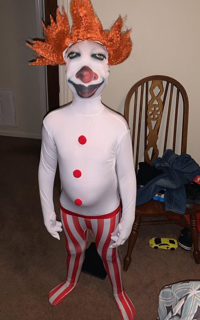 Child in a white and red striped clown costume with an orange wig, an example of a bad clothing design.