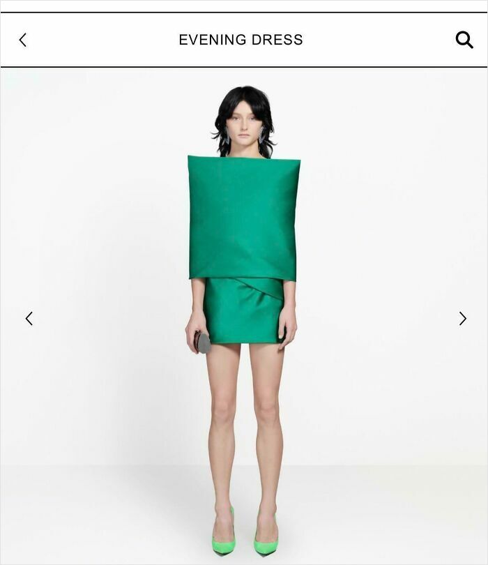 Model wearing a green, boxy, and bad clothing design dress, appearing very stiff.