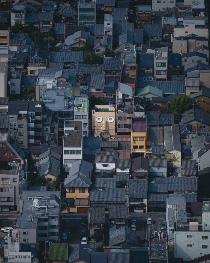 Dense neighborhood with one building featuring a face painted on facade urban hell